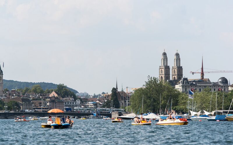 Passengers taking in views of Lake Zurich and the surrounding landscape from a cruise boat.